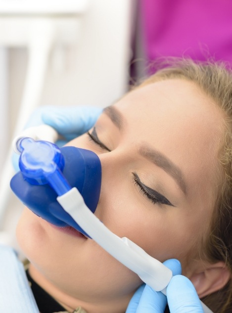 Young woman wearing nitrous oxide sedation mask in dental chair