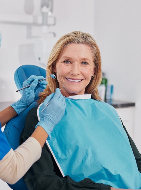 Woman in dental chair smiling about to undergo exam