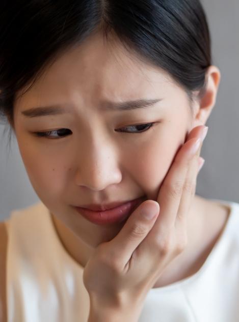Young woman holding the side of her face in pain