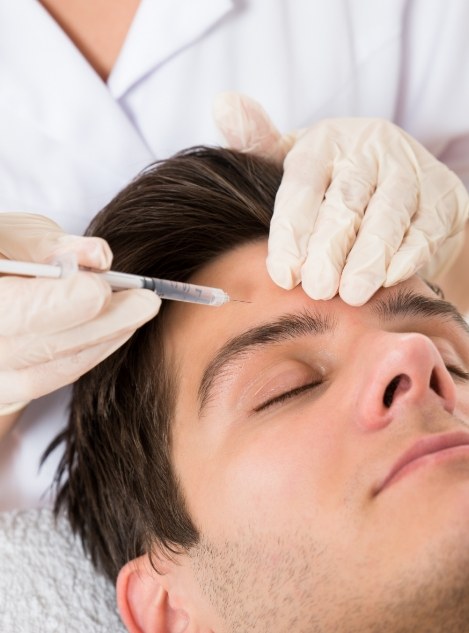 Man with eyes closed receiving injection in his forehead