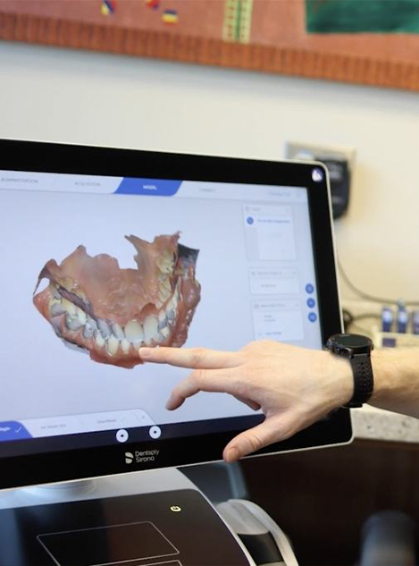 Dental team member pointing to digital dental impressions on computer monitor