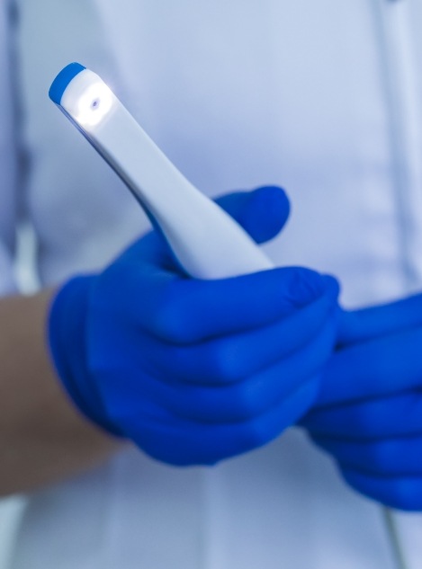 Dentist holding white pen like intraoral camera