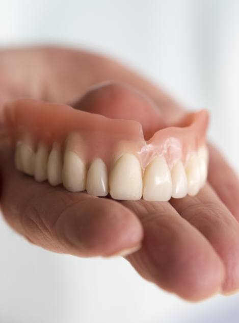 Person holding a full denture in their hand