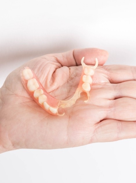 Person holding a partial denture in their hand