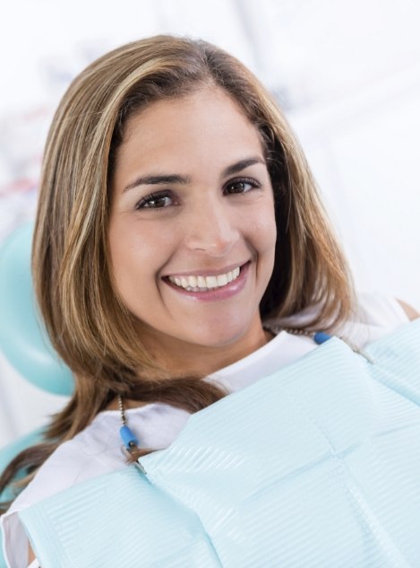 Young woman sitting in dental chair and grinning