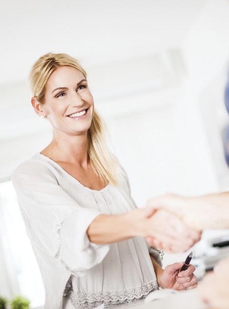 Smiling blonde woman shaking hands with dental team member