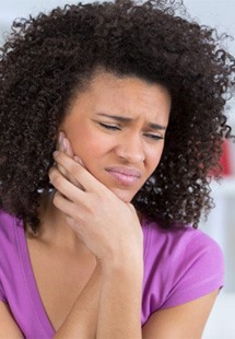 a woman holding her jaw due to pain