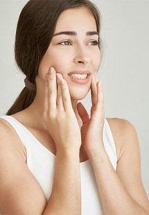 a woman holding her cheeks due to a dental emergency