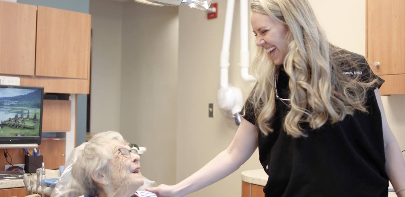 Doctor Grisham laughing with a senior dental patient