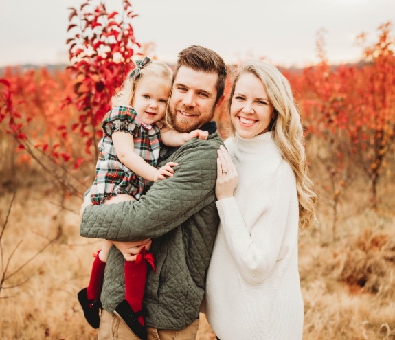 Doctor Grisham with her husband and child outdoors in autumn