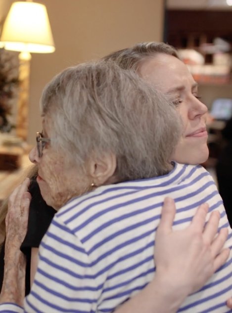 Doctor Grisham hugging an elderly woman in dental office