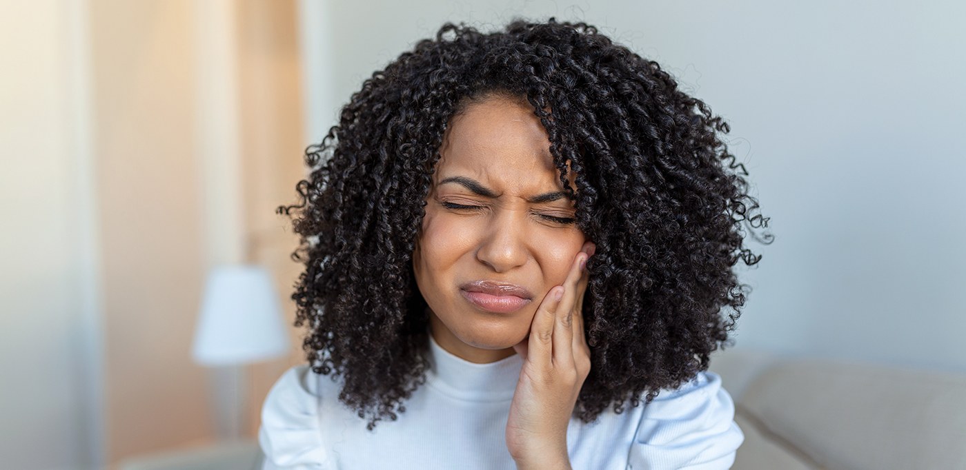 Woman in light blue shirt with pain in jaw