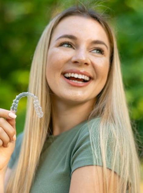Woman looking over her shoulder, holding clear aligner