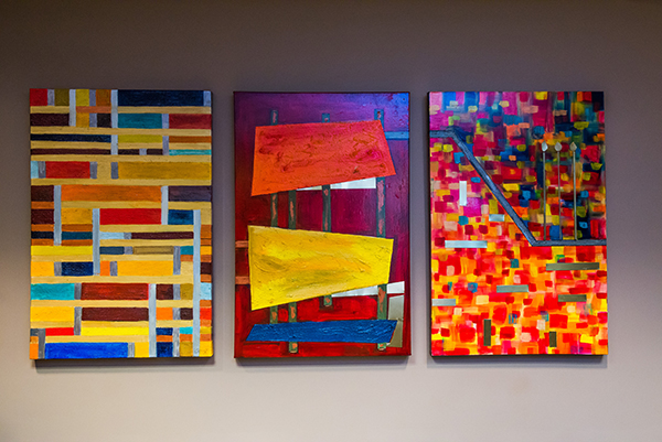 Three colorful paintings on a wall