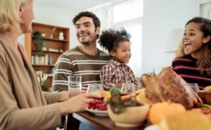 a family sitting down at a table together and enjoying Thanksgiving dinner