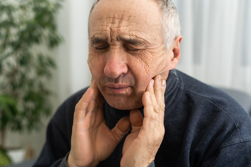 Patient holding their jaw due to untreated TMJ disorder