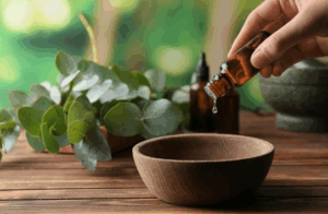 Close up of individual pouring essential oils into a wooden bowl