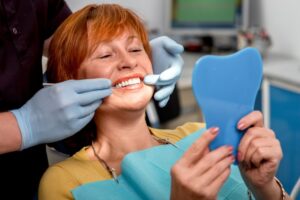 Woman with implants smiling in dentist's chair. 