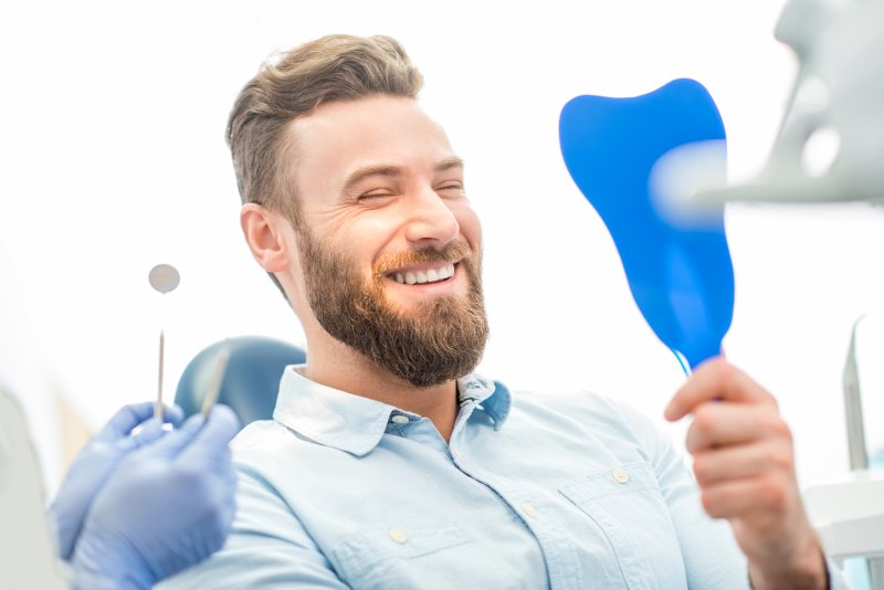 Patient smiling in mirror after cosmetic dentistry